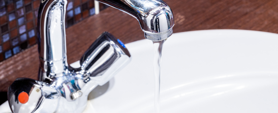 Water running from a tap with low pressure, showcasing a frequent plumbing issue in commercial buildings.